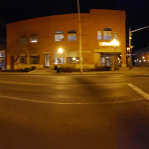Intersection of Broadway and Division Street in downtown Saratoa Springs on March 18th, 2020. Usually downtown is busy with nightlife even on weeknights. There is no one out on the sidewalks, and a handful of cars parked in the street. It's a relative ghost town.
